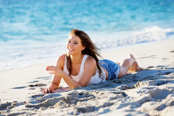 Genç bir kadın sahilde dinleniyor.