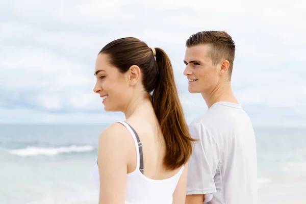 Pareja joven buscando reflexivo mientras están de pie uno al lado del otro en la playa — Foto de Stock