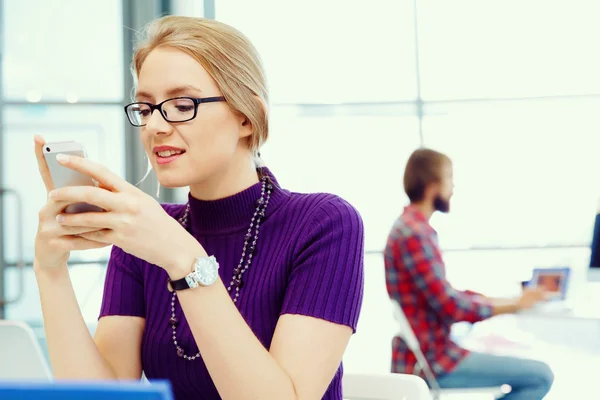 Zakenvrouw in kantoor houden van mobiele telefoon — Stockfoto