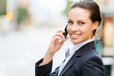 Açık havada gülümseyen bir iş kadını portresi.