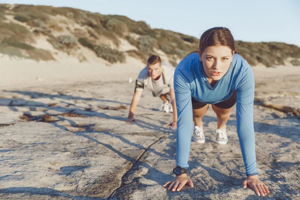 Pareja joven haciendo flexiones en la playa del océano —  Fotos de Stock