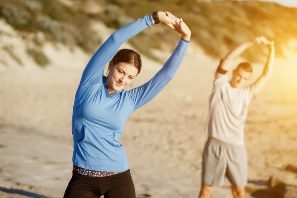 Junges Paar trainiert gemeinsam am Strand — Stockfoto