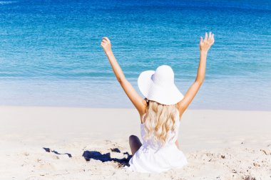 Genç bir kadın sahilde dinleniyor.