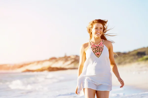 Jeune femme marchant le long de la plage — Photo