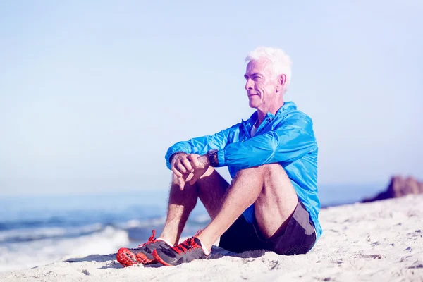 Muž sedí na pláži sportovní oblečení — Stock fotografie