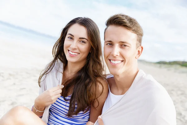 Romántica pareja joven sentada en la playa — Foto de Stock