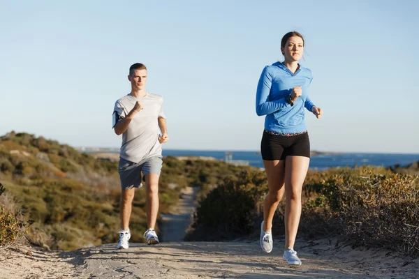 Urheilu juoksija lenkkeily rannalla treenata hänen kumppaninsa kanssa — kuvapankkivalokuva