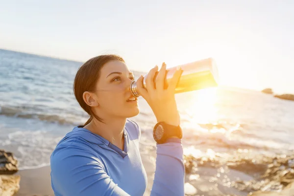Mujer bebiendo agua en la playa — Foto de Stock