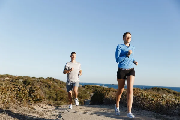 Corridore sportivo che fa jogging sulla spiaggia allenandosi con il suo partner — Foto Stock