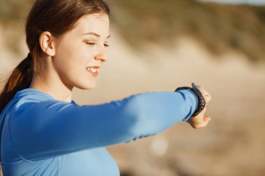 Kalp atış hızı monitörünü plajda çalışan kadınla Runner