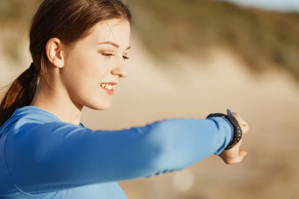 Loper vrouw met hartslagmeter uitgevoerd op strand — Stockfoto