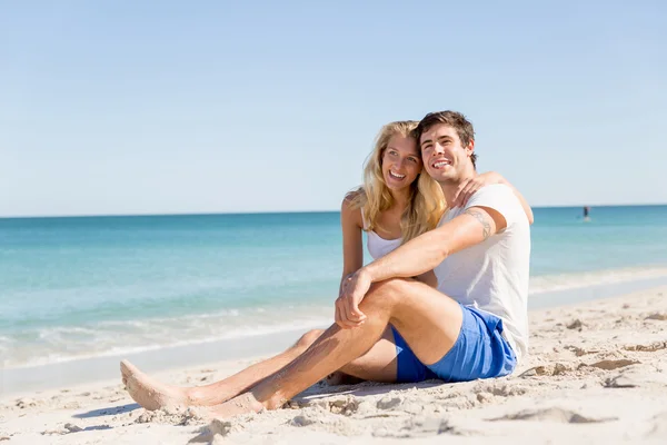 Romantiska unga paret sitter på stranden — Stockfoto