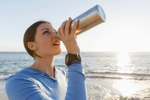 Mujer bebiendo agua en la playa — Foto de Stock