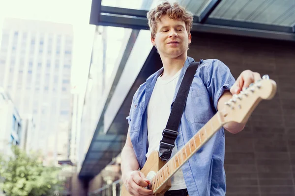 Joven músico con guitarra en la ciudad —  Fotos de Stock