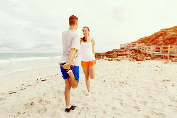 Des coureurs. Jeune couple exerçant et stertching sur la plage — Photo