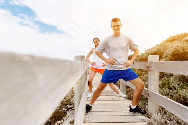 Des coureurs. Jeune couple exerçant et stertching sur la plage — Photo