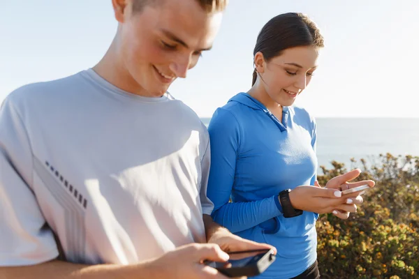 Young couple with smartphones outdoors — Stock Photo, Image