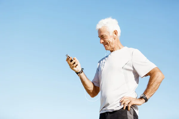 Manliga löpare med sin smarta mobiltelefon som står utomhus — Stockfoto