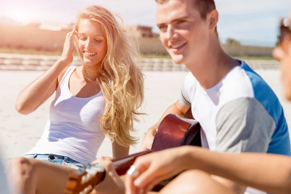 Beautiful young people with guitar on beach — Stock Photo, Image