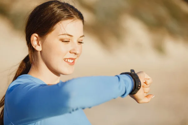 Mujer corredora con monitor de frecuencia cardíaca corriendo en la playa —  Fotos de Stock