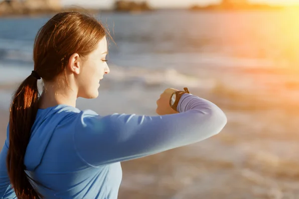 Mujer corredora con monitor de frecuencia cardíaca corriendo en la playa — Foto de Stock