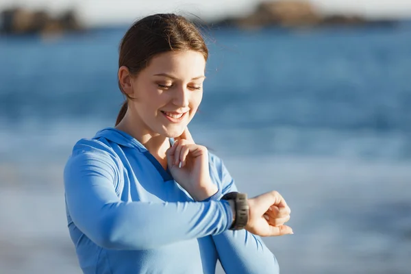 Loper vrouw met hartslagmeter uitgevoerd op strand — Stockfoto