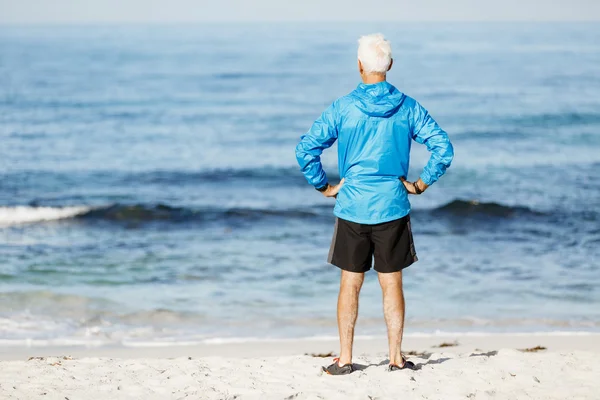 Bello uomo cercando premuroso mentre in piedi da solo sulla spiaggia — Foto Stock