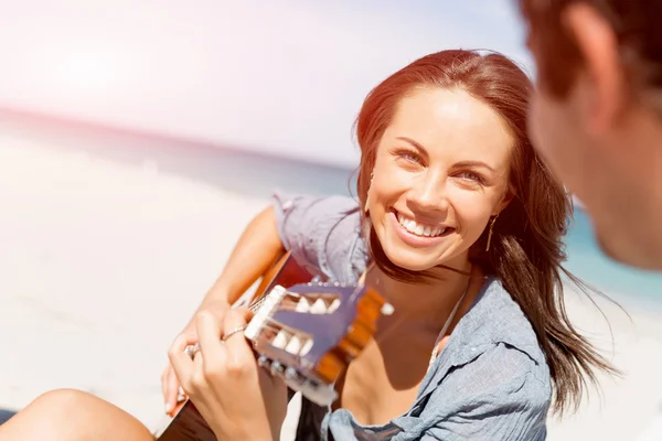 Schöne junge Frau spielt Gitarre am Strand — Stockfoto