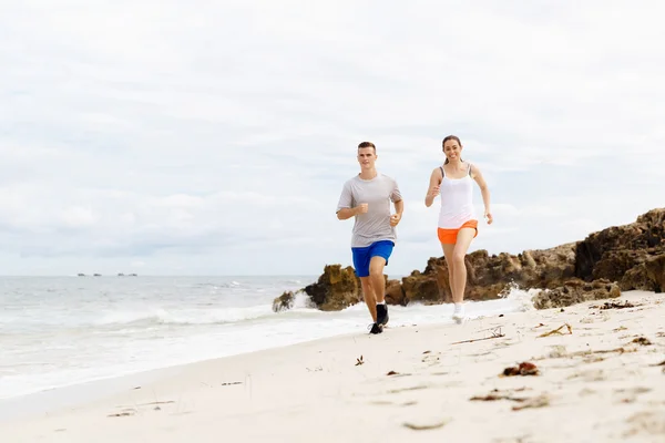 Corredores. Jovem casal correndo na praia — Fotografia de Stock