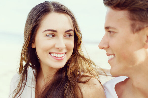 Романтическая молодая пара сидит на пляже
