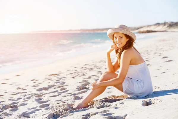 Jeune femme assise sur la plage — Photo