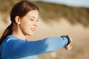 Kalp atış hızı monitörünü plajda çalışan kadınla Runner