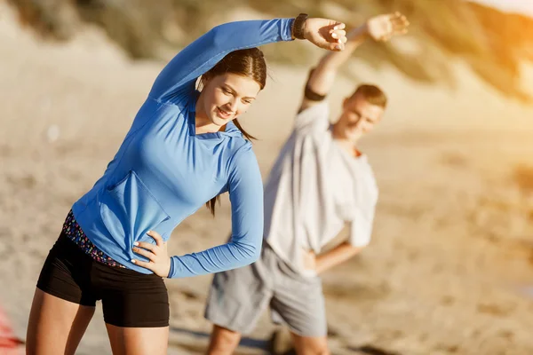 Jong (echt) paar op het strand training samen — Stockfoto