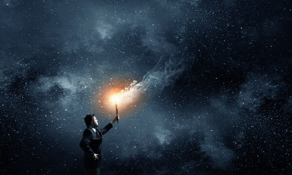 Young businessman in darkness holding burning torch in hand
