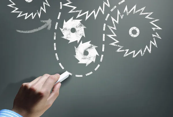 Man drawing gears on blackboard — Stock Photo, Image