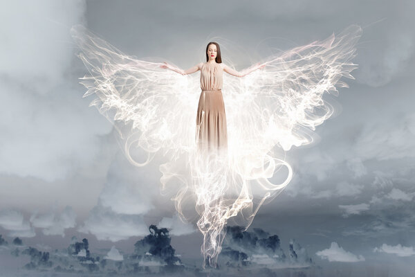 Beautiful woman in long dress with wings in clear sky