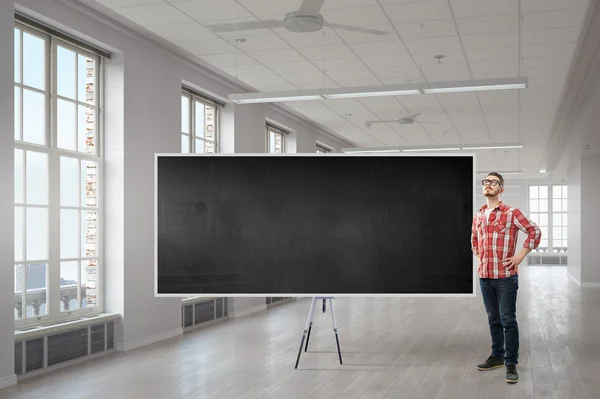 Guy in interieur in de buurt van schoolbord — Stockfoto