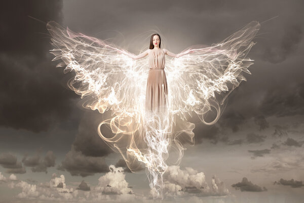 Beautiful woman in long dress with wings in gray sky