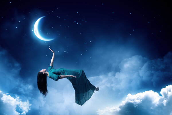 Elegant woman in green long dress floating in night sky