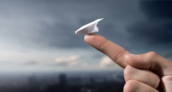Бумажный самолет на пальце — стоковое фото