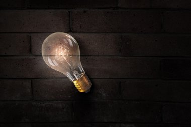 Tuğla yüzeyinde parlayan ampul