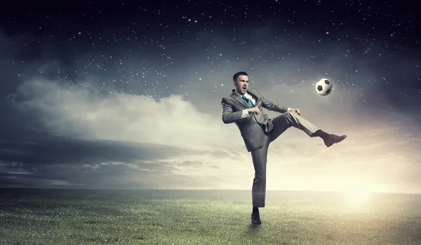 Businessman kicking ball — Stock Photo, Image