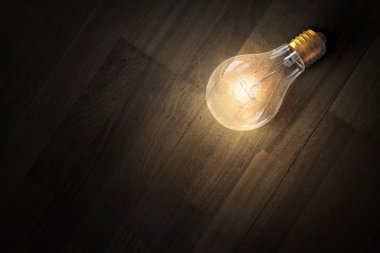 Ahşap yüzey üzerinde ampul. Karışık teknik