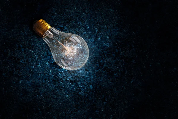 Light bulb on soil . Mixed media — Stock Photo, Image