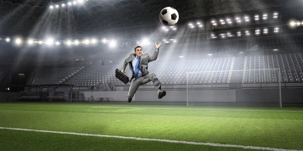 Businessman kicking ball . Mixed media — Stock Photo, Image