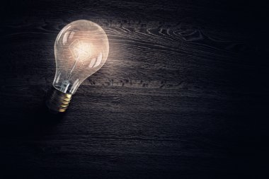 Ahşap yüzey üzerinde ampul. Karışık teknik