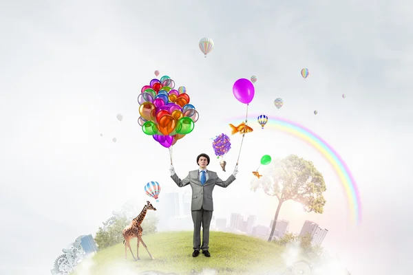 Comedian man with color balloons . Mixed media — Stock Photo, Image