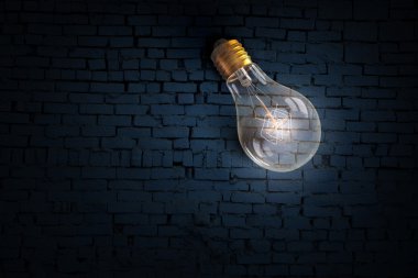 Parlayan ampul tuğla yüzeyinde. karışık teknik