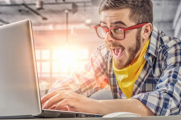 Hipster guy användning laptop. Mixed media — Stockfoto