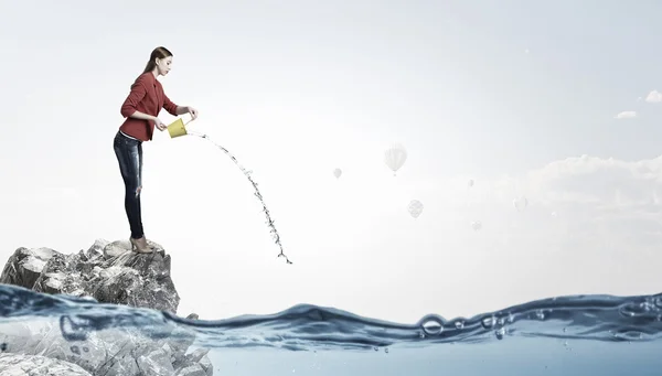Girl pouring water from bucket . Mixed media — Stock Photo, Image
